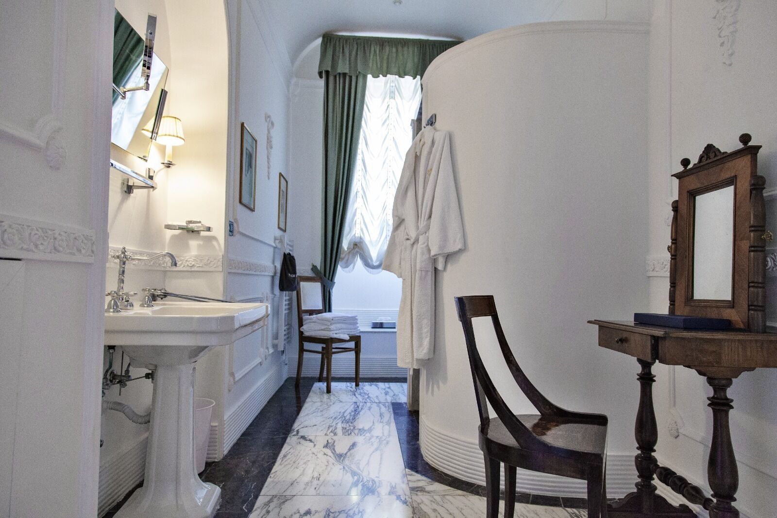 A bathroom with a sink, mirror, and chair.