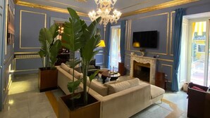 Un salon luxueux avec un grand canapé, un lustre et une cheminée.
