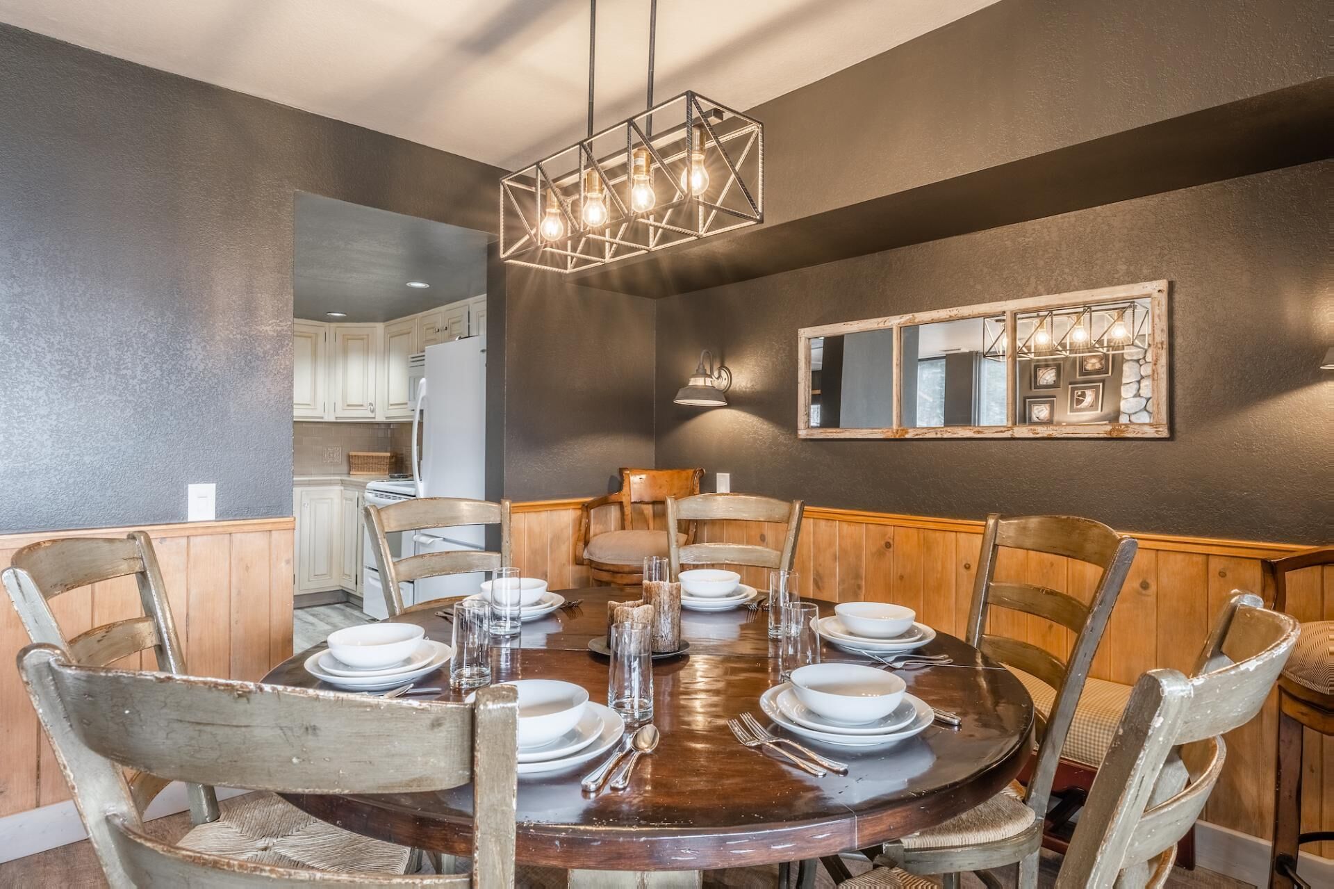 Une salle à manger avec une table ronde en bois, dressée pour six personnes, entourée de chaises en bois.
