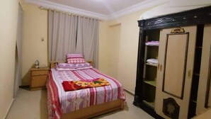 Ein Schlafzimmer mit Bett, Nachttisch, Kleiderschrank und Deckenleuchte.