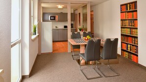 A compact living space with a dining area, kitchenette, and a bookshelf.