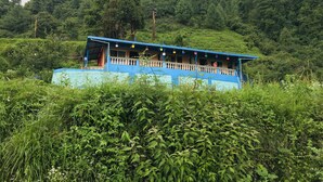 A blue building with a balcony, surrounded by lush greenery and hills. - Mountains, jungle , Trekking and luxury stay near to nature (Dhanolti)