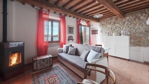 A cozy living room with a stone wall, a wooden ceiling, a sofa with cushions, a small table, and a fireplace. - Folaga Apartments, "Puntone" (Sant'Arcangelo)