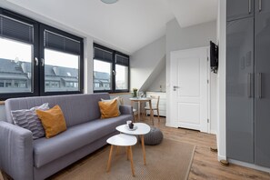 Ein modernes Wohnzimmer mit einem grauen Sofa, einem kleinen weißen Tisch und einem grauen Schrank.