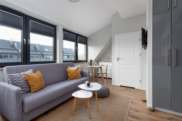 A modern living room with a grey sofa, a small white table, and a grey cabinet.