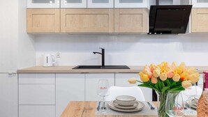 A modern kitchen with white cabinets, a black faucet, and a wooden countertop.