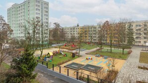 Zona de juegos infantiles con toboganes y estructuras de recreo, rodeada de edificios de apartamentos.