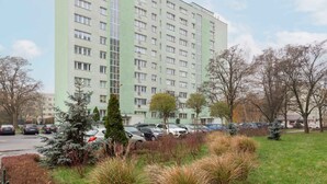 Un edificio residencial de varios pisos con fachada uniforme, estacionamiento y zonas verdes circundantes.