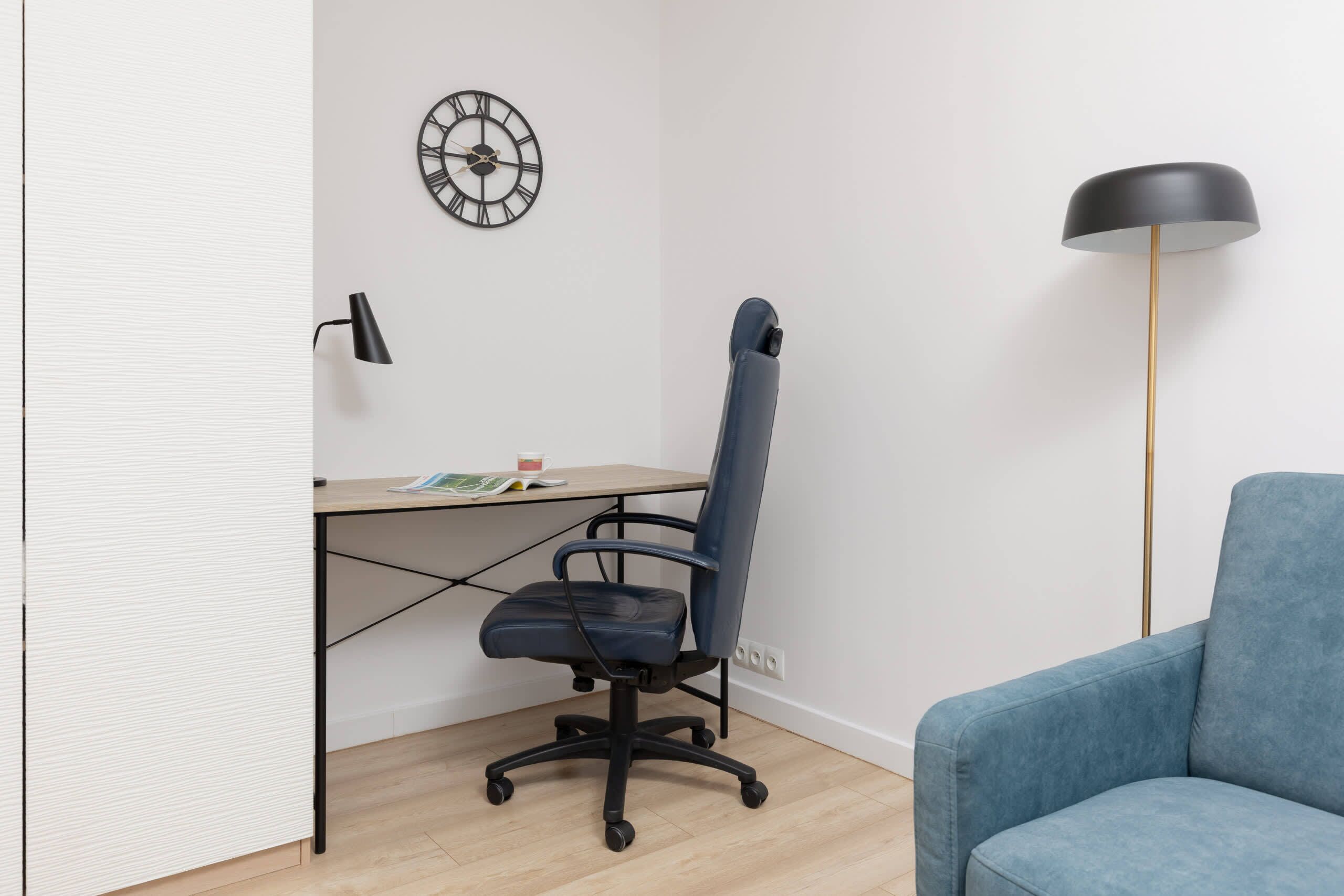 A corner office with a desk, chair, and a clock on the wall.