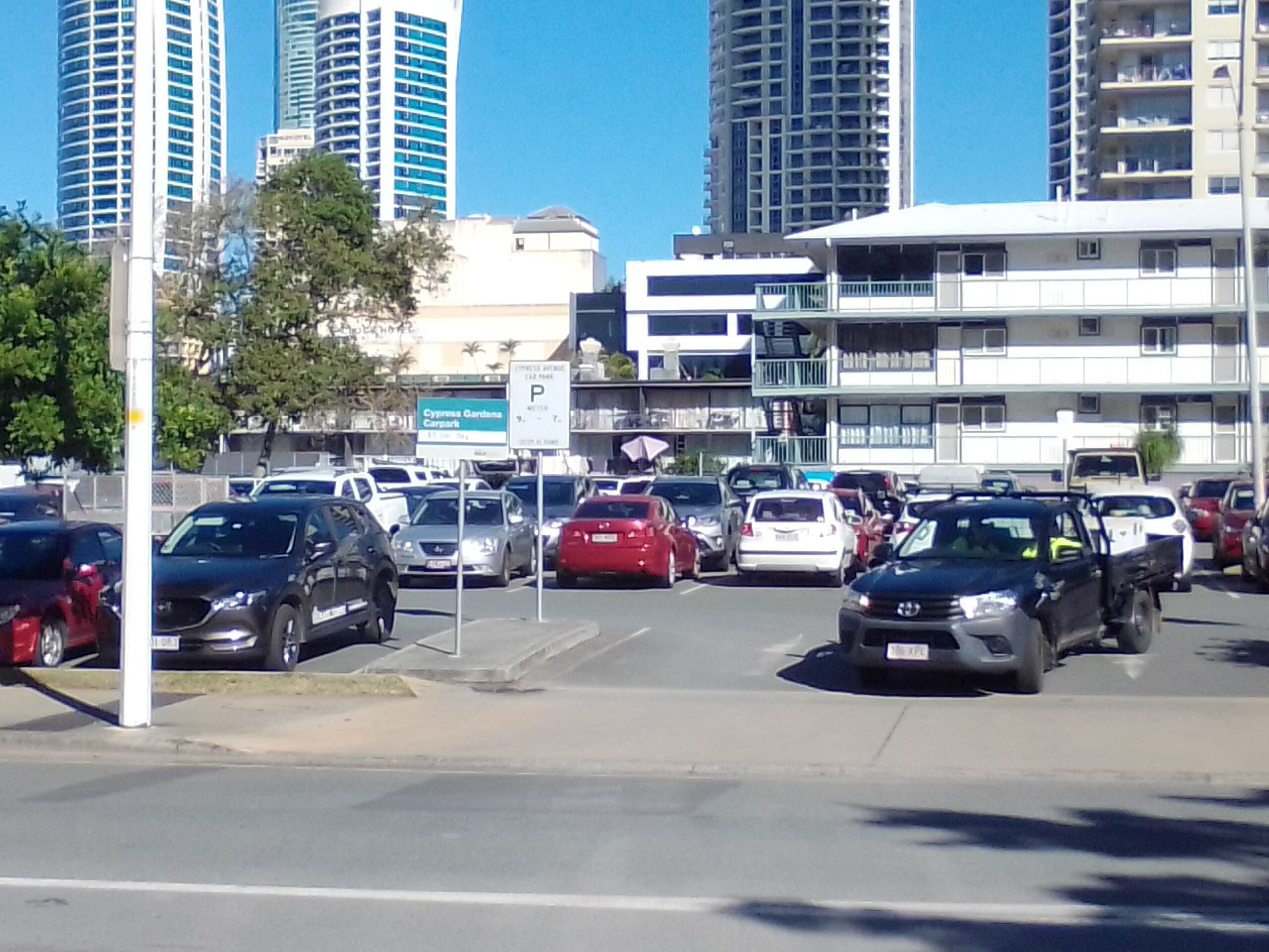 Una concurrida calle urbana con varios coches y edificios altos al fondo.