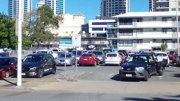 Una concurrida calle urbana con varios coches y edificios altos al fondo.