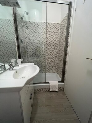 City tweepersoonskamer | Badkamer | Een douche, een haardroger, handdoeken, zeep
