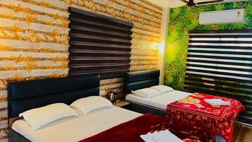 Habitación de hotel con dos camas, una colcha roja con estampado floral, una pared de madera con flores amarillas y un equipo de aire acondicionado.