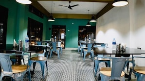 Un comedor con mesas y sillas, ventilador de techo e iluminación colgante.