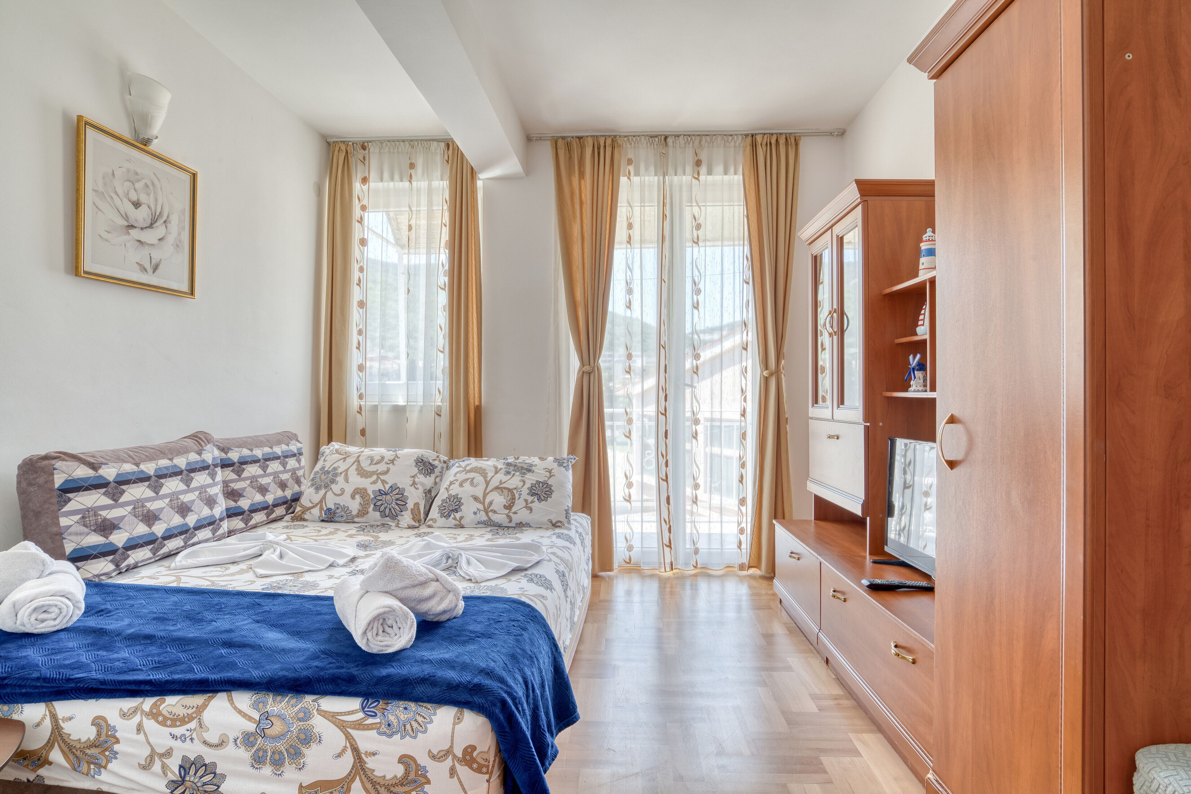 A bedroom with a bed, curtains, a wardrobe, and a television.