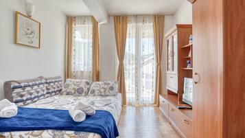 A bedroom with a bed, curtains, a wardrobe, and a television.
