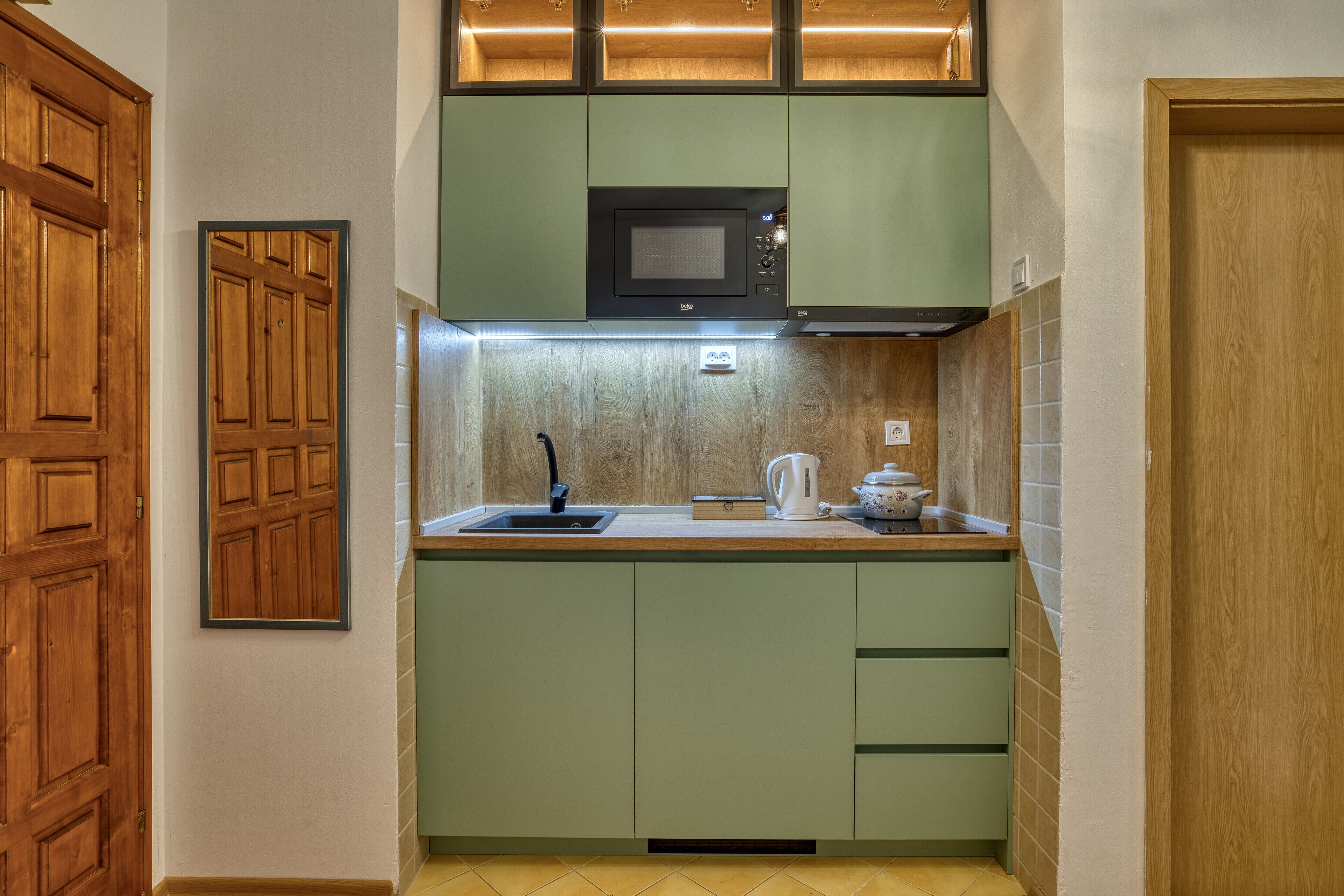 A compact kitchen with a microwave, sink, and cabinets.