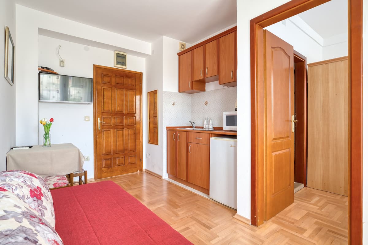 A compact kitchen with wooden cabinets, a microwave, and a refrigerator.