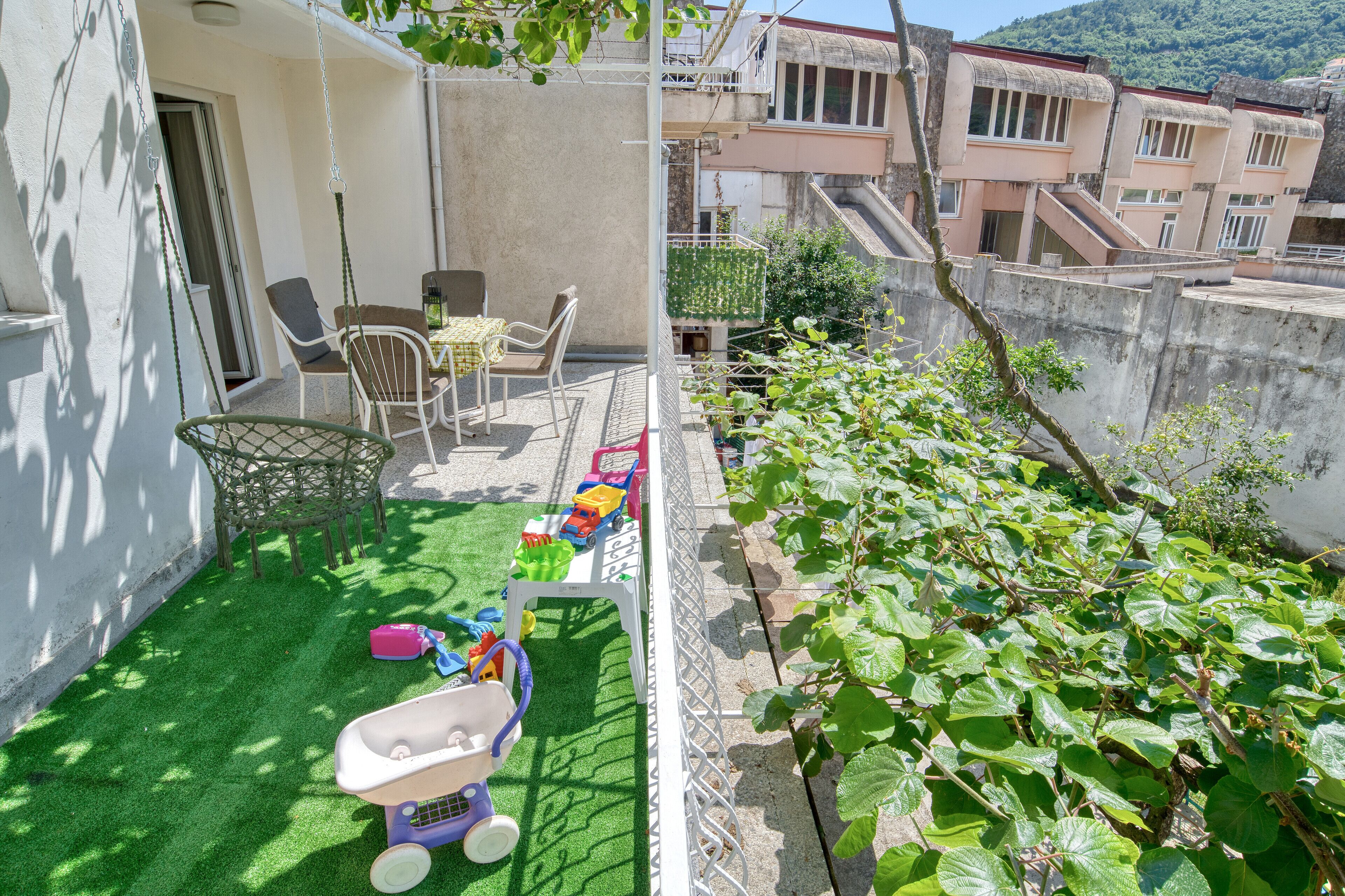 Un balcone con un tavolino e sedie, un'amaca e un'area giochi con giocattoli e una macchinina.
