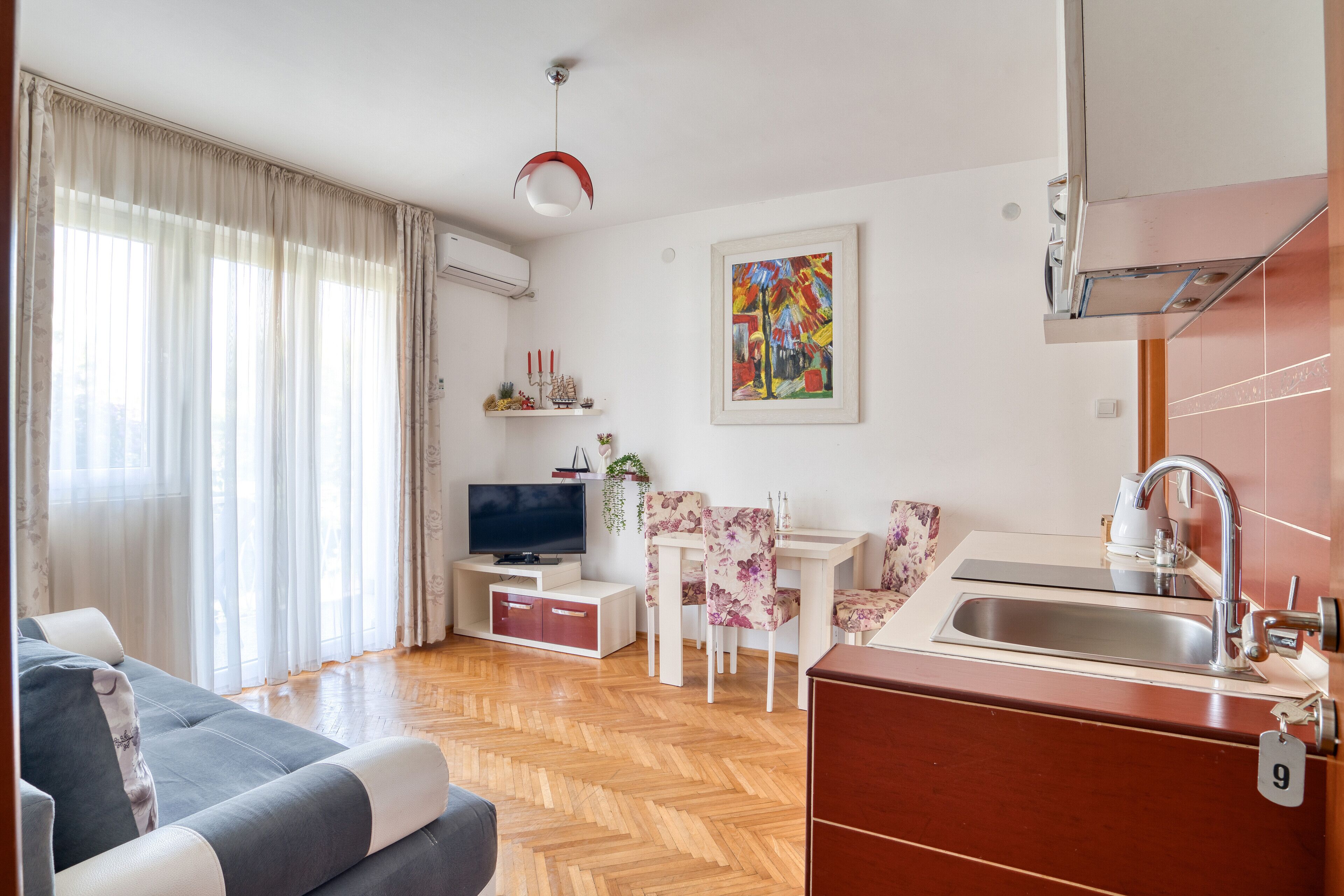 A modern living room with a sofa, TV, dining area, and kitchen.