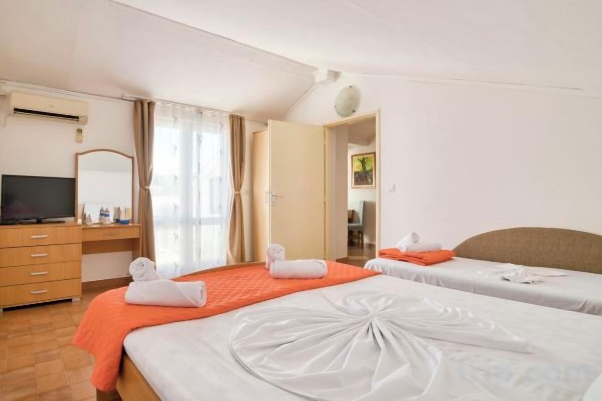 A hotel room with two beds, a television, a desk, and a bathroom visible through an open door.