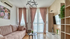 Ein modernes Wohnzimmer mit einer Couch, einem Couchtisch und einem Fernseher auf einer Holzkommode.