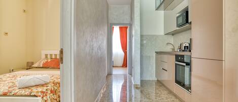 A hotel room with a bed, a bathroom, and a kitchenette.