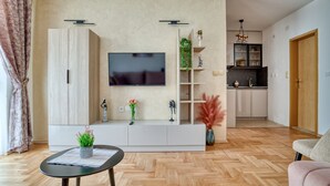 Ein modernes Wohnzimmer mit Flachbildfernseher, einer weißen Unterhaltungseinheit und einem Fischgrätparkettboden.