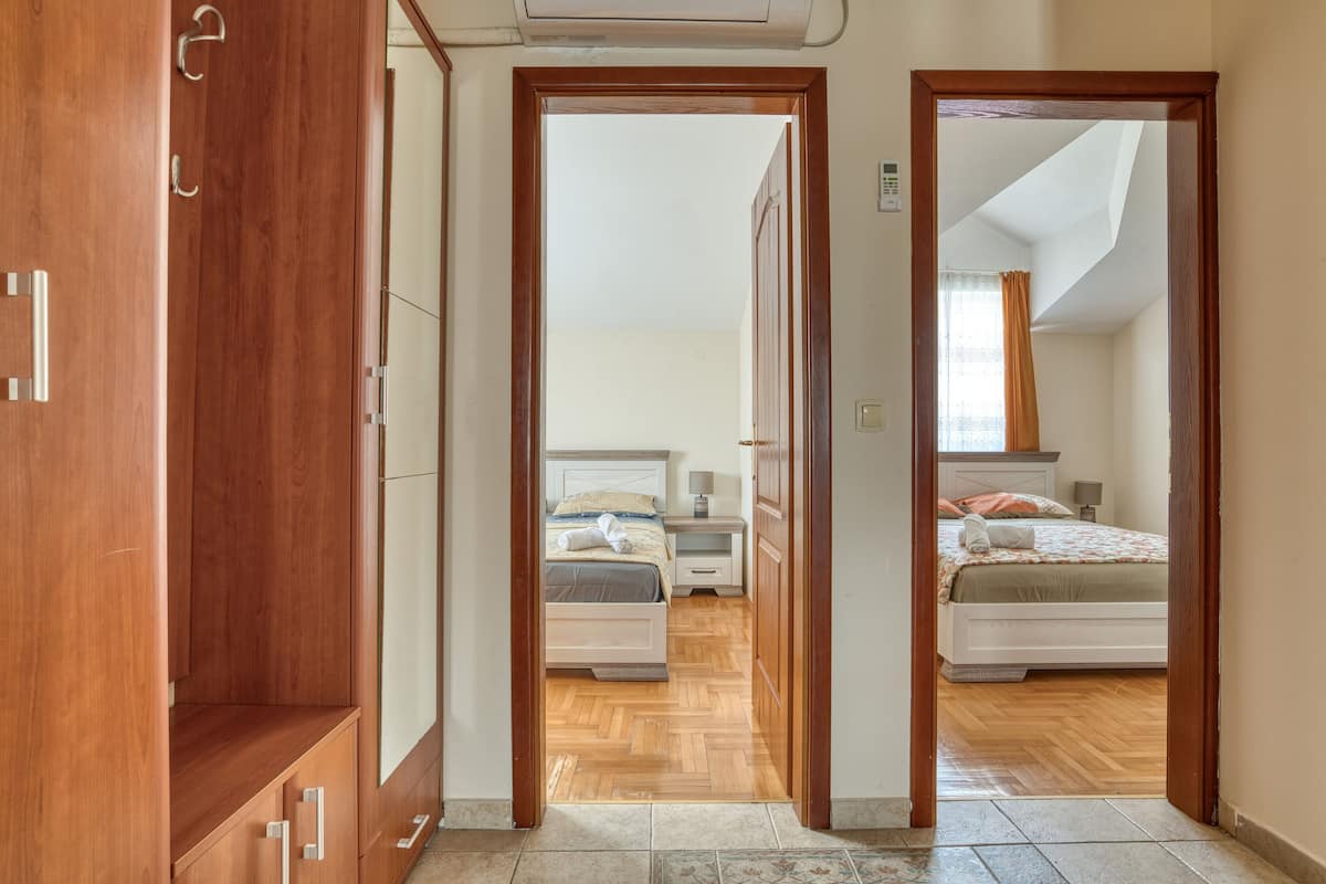 A hallway leading to two bedrooms with wooden flooring and a ceiling fan.