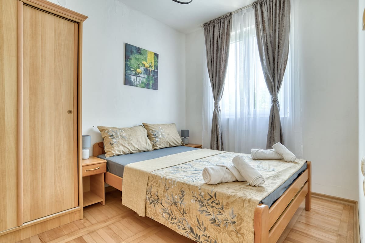 A bedroom with a wooden bed, a nightstand, a wardrobe, and a painting on the wall.