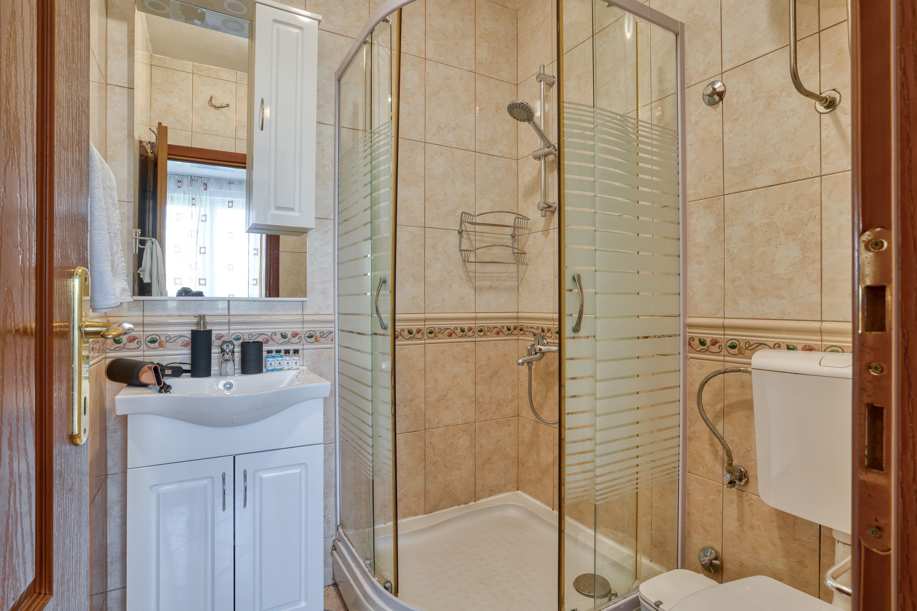A modern bathroom with a glass-enclosed shower, a white sink, and a toilet.