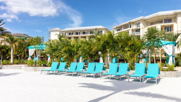 A beachfront hotel with rows of blue lounge chairs, palm trees, and a clear blue sky. - Margaritaville Townhome Retreat (Kissimmee)