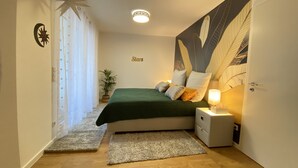 A bedroom with a bed, nightstands, a wall-mounted lamp, a star decoration, and a plant. - Mein Apartment, Stars for 4 Person (Frankenthal)