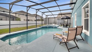 En trädgård med en pool, en täckt uteplats och utemöbler.
