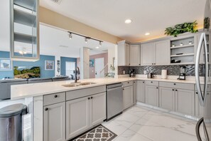 A modern kitchen with grey cabinets, a white countertop, and a black and white backsplash. - 4BR | South Facing Pool | Close to Attractions (Kissimmee)