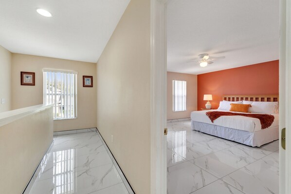 A bedroom with a bed, a ceiling fan, and a window. - 4BR | South Facing Pool | Close to Attractions (Kissimmee)