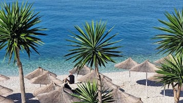 Praia particular, areia branca, espreguiçadeiras, guarda-sóis