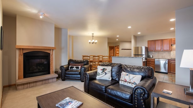 A modern living room with a fireplace, leather sofas, and a dining area. - Family Ski Condo With Continental Divide View - Zephyr Mountain Lodge Value-rated 2508 3 Bedroom Condo (Winter Park)