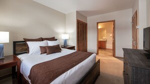 A hotel room with a large bed, bedside tables, a TV, and a bathroom visible through an open door. - Family Ski Condo With Continental Divide View - Zephyr Mountain Lodge Value-rated 2508 3 Bedroom Condo (Winter Park)