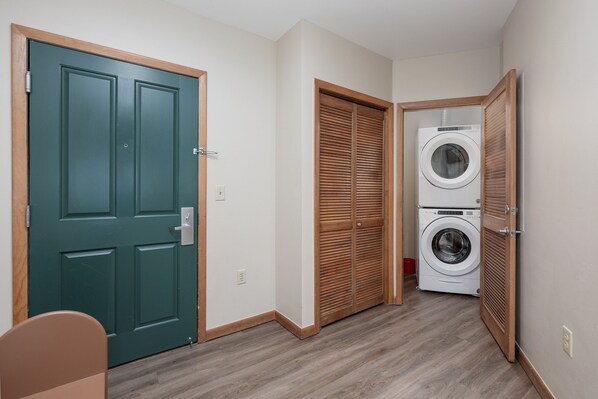 Un cuarto de lavado con una puerta verde, una puerta de madera y una lavadora.
