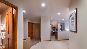 A hallway leading to a kitchen with wooden cabinets and a microwave. - Family Ski Condo With Continental Divide View - Zephyr Mountain Lodge Value-rated 2508 3 Bedroom Condo (Winter Park)