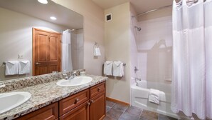 A bathroom with two sinks, a wooden vanity, a large mirror, a shower with a glass door, and a bathtub. - Family Ski Condo With Continental Divide View - Zephyr Mountain Lodge Value-rated 2508 3 Bedroom Condo (Winter Park)