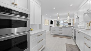 Una cocina moderna con armarios blancos, electrodomésticos de acero inoxidable e iluminación colgante.