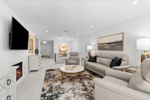 A modern living room with a flat-screen TV, a fireplace, a sofa, and a coffee table. - Upscale Oceanfront – Club Longboat #334 RVA (Longboat Key)