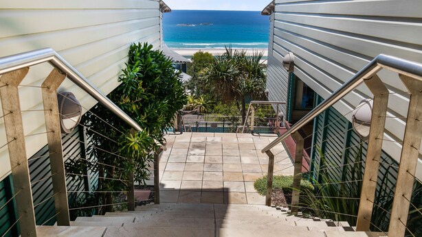 Un escalier menant à un balcon d’où l’on a vue sur une plage et sur l’océan.