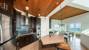 Une cuisine moderne avec des meubles de couleur sombre, des appareils électroménagers en acier inoxydable et un grand îlot central.
