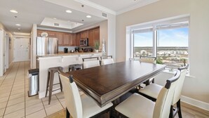 Una cocina amplia con una isla grande, armarios blancos y vistas de la ciudad a través de amplios ventanales.