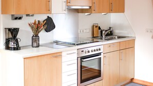 Une cuisine compacte avec des meubles en bois, un four encastré, une machine à café et un petit plan de travail.