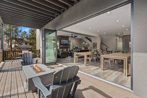 Een moderne buitenpatio met een vuurkorf, zitplaatsen en uitzicht op het interieur.
