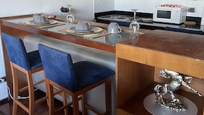 Una cocina moderna con una isla central, taburetes de bar, microondas y electrodomésticos de acero inoxidable.